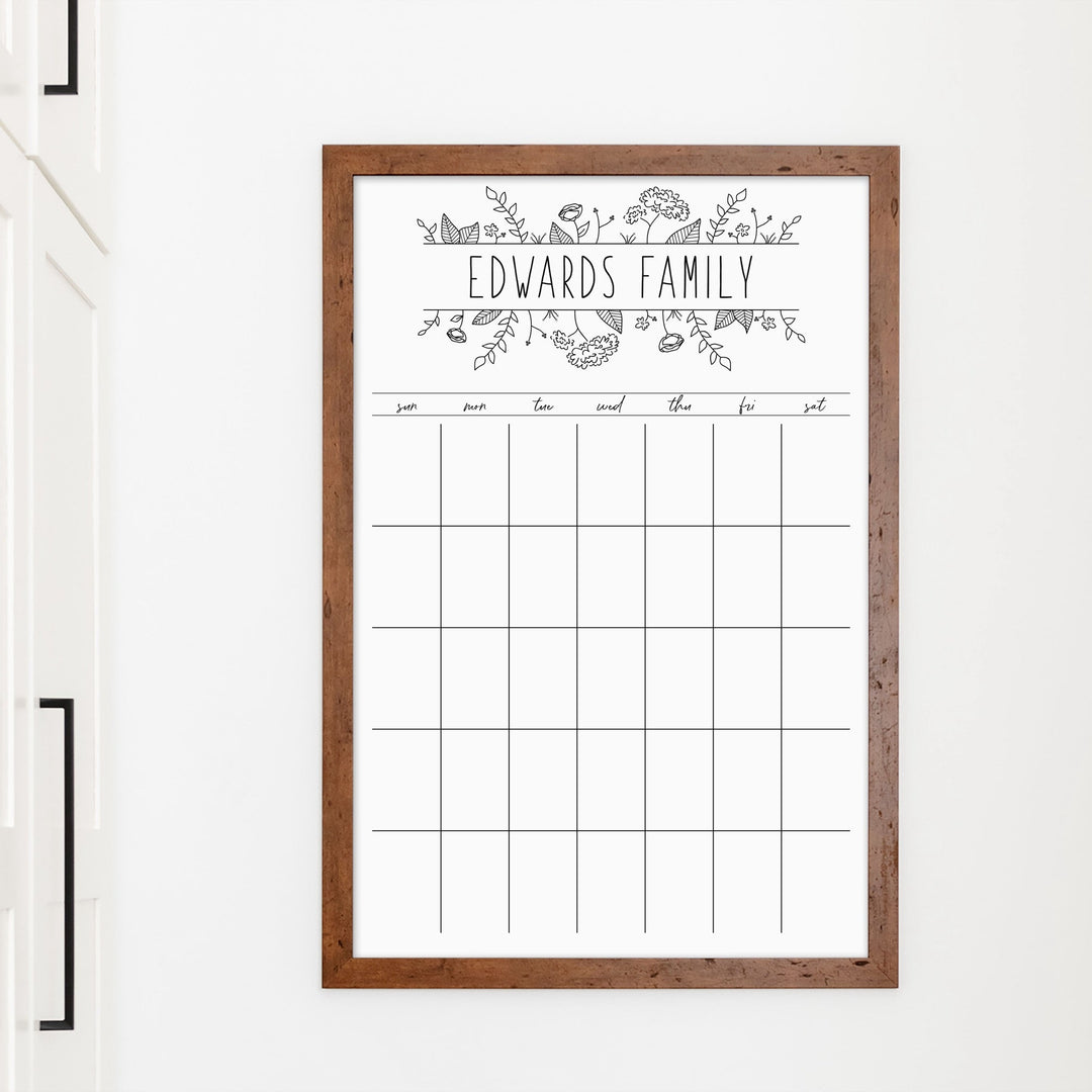 A framed whiteboard monthly calender hanging on the wall