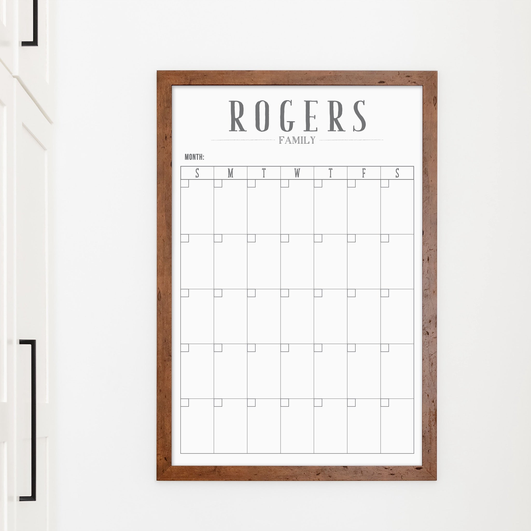 A framed whiteboard monthly calender hanging on the wall