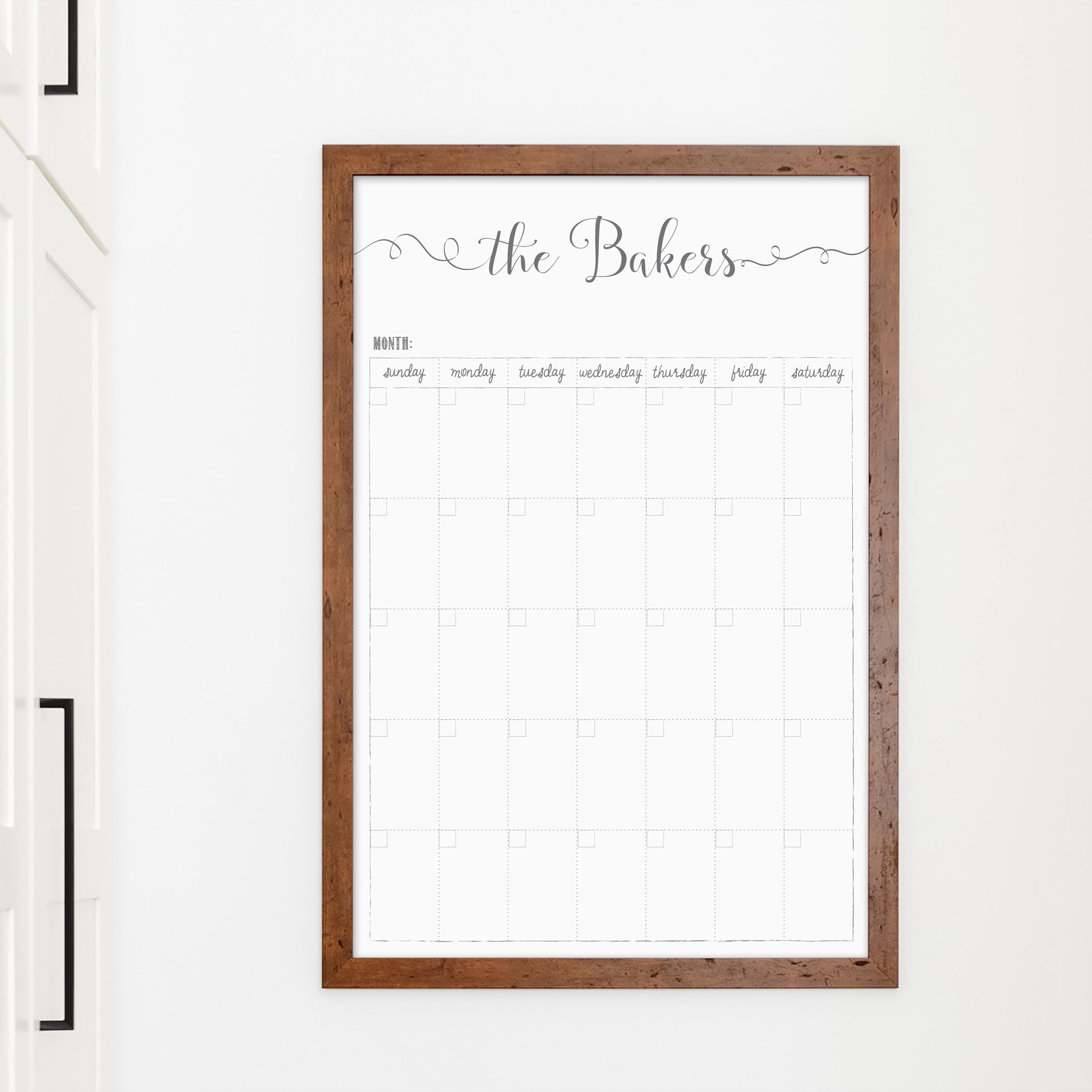 A framed whiteboard monthly calender hanging on the wall