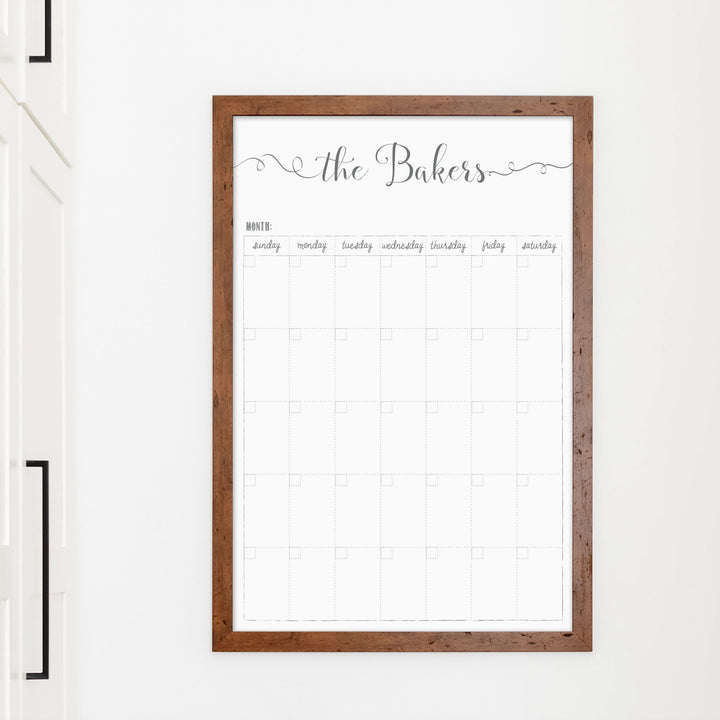 A framed whiteboard monthly calender hanging on the wall
