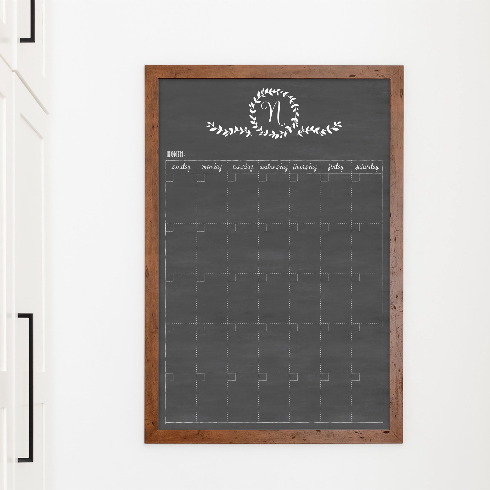 A framed whiteboard monthly calender hanging on the wall
