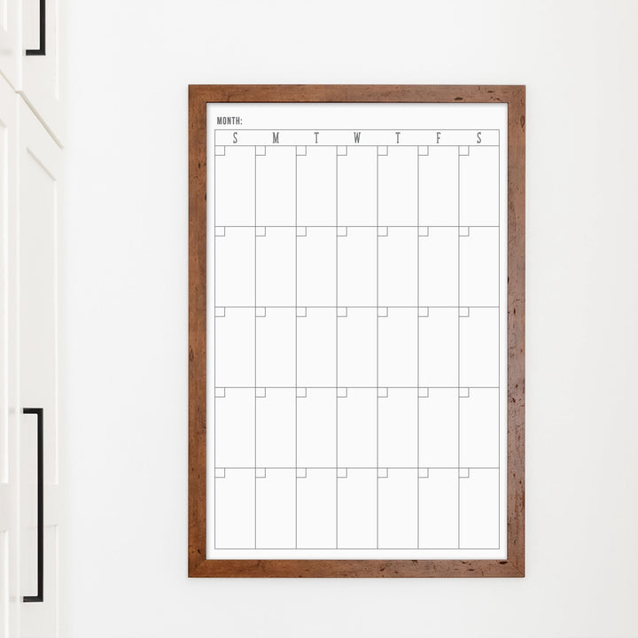 A framed whiteboard monthly calender hanging on the wall