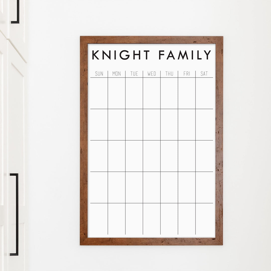 A framed whiteboard monthly calender hanging on the wall