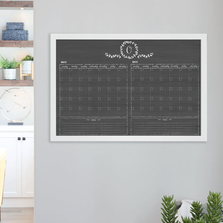 A framed chalkboard dry-erase calendar with a two month design format hanging on the wall