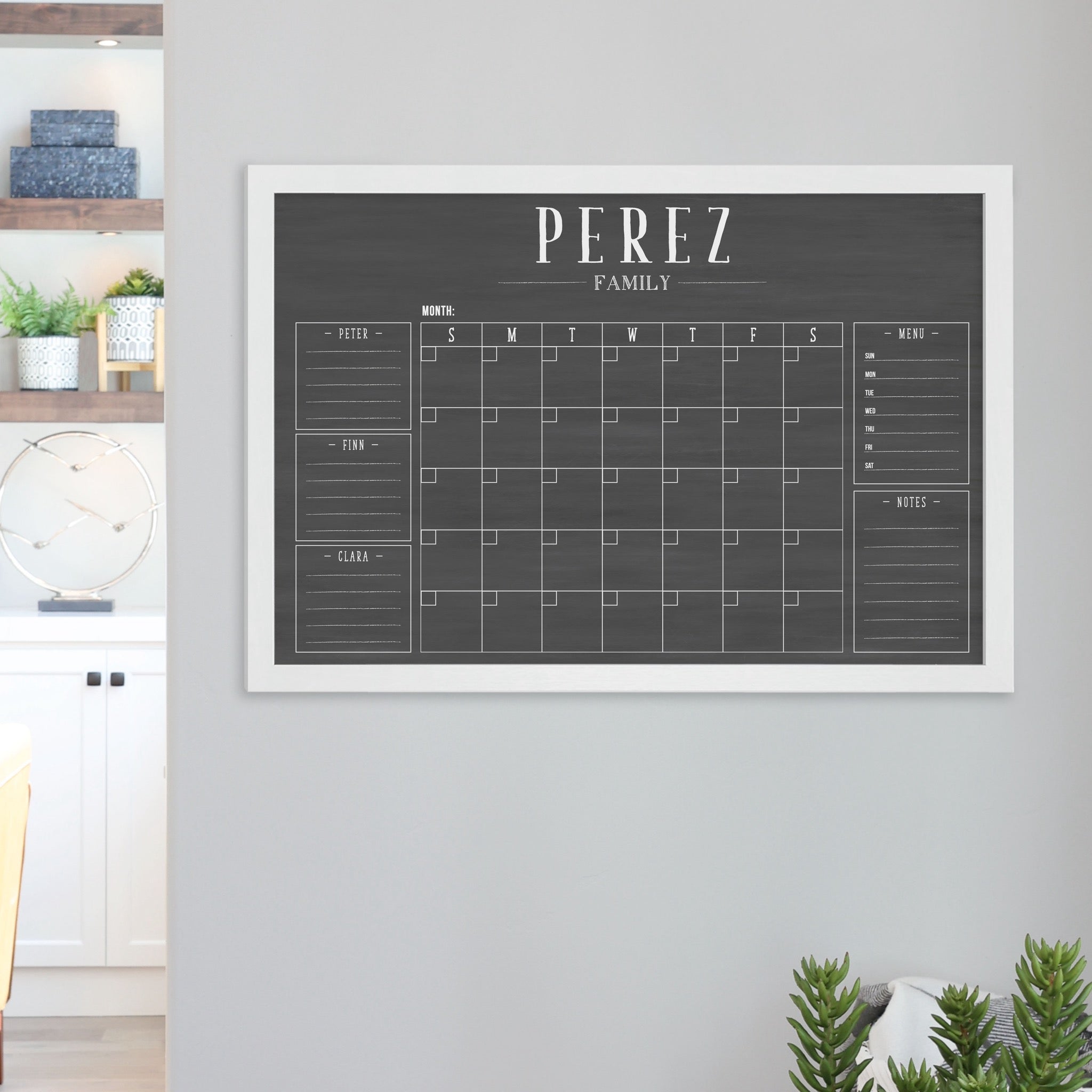 A framed dry-erase family command center with a faux chalkboard look hanging on the wall