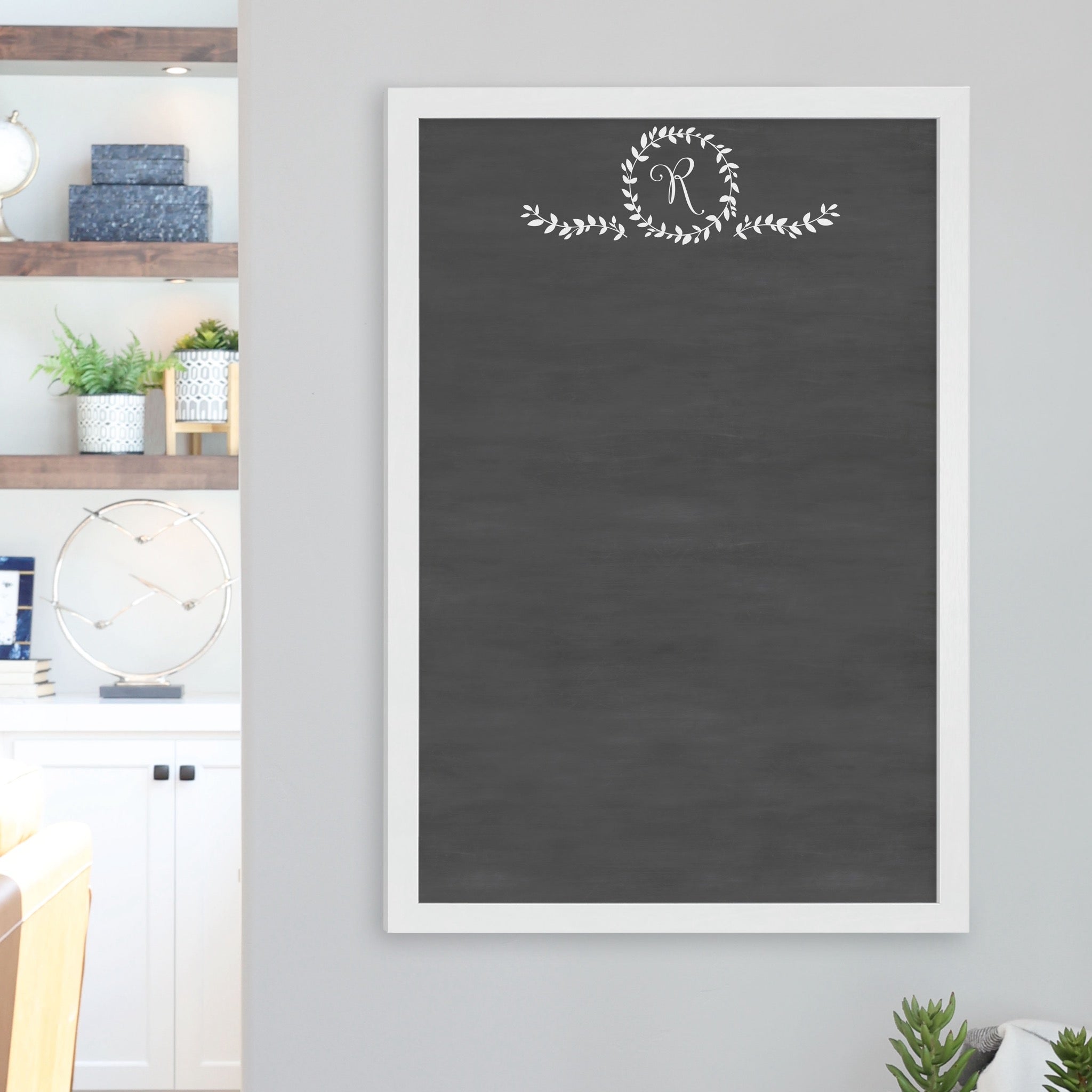 A framed dry-erase chalkboard calendar with a two month design format hanging on the wall