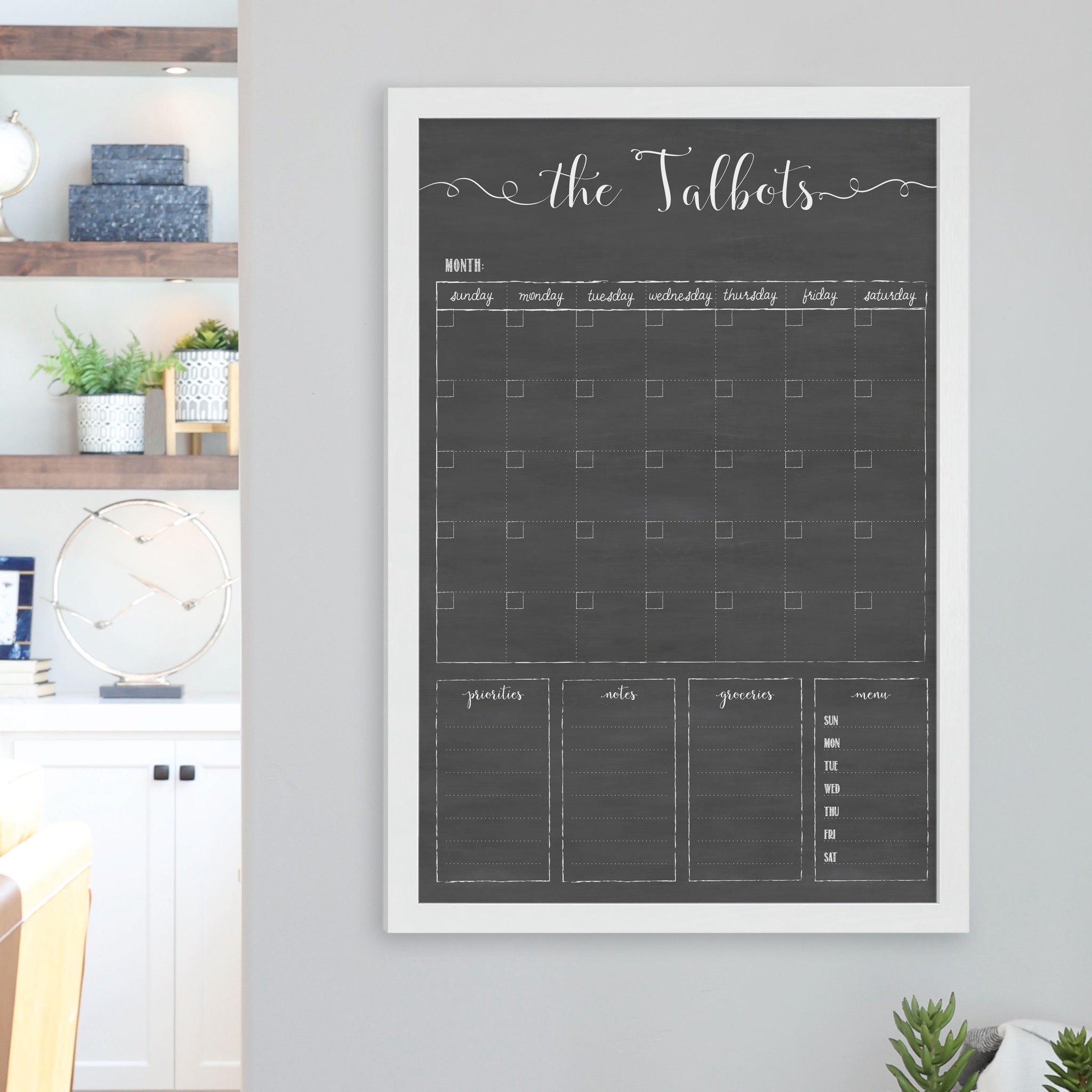 A framed dry-erase family command center with a faux chalkboard look hanging on the wall