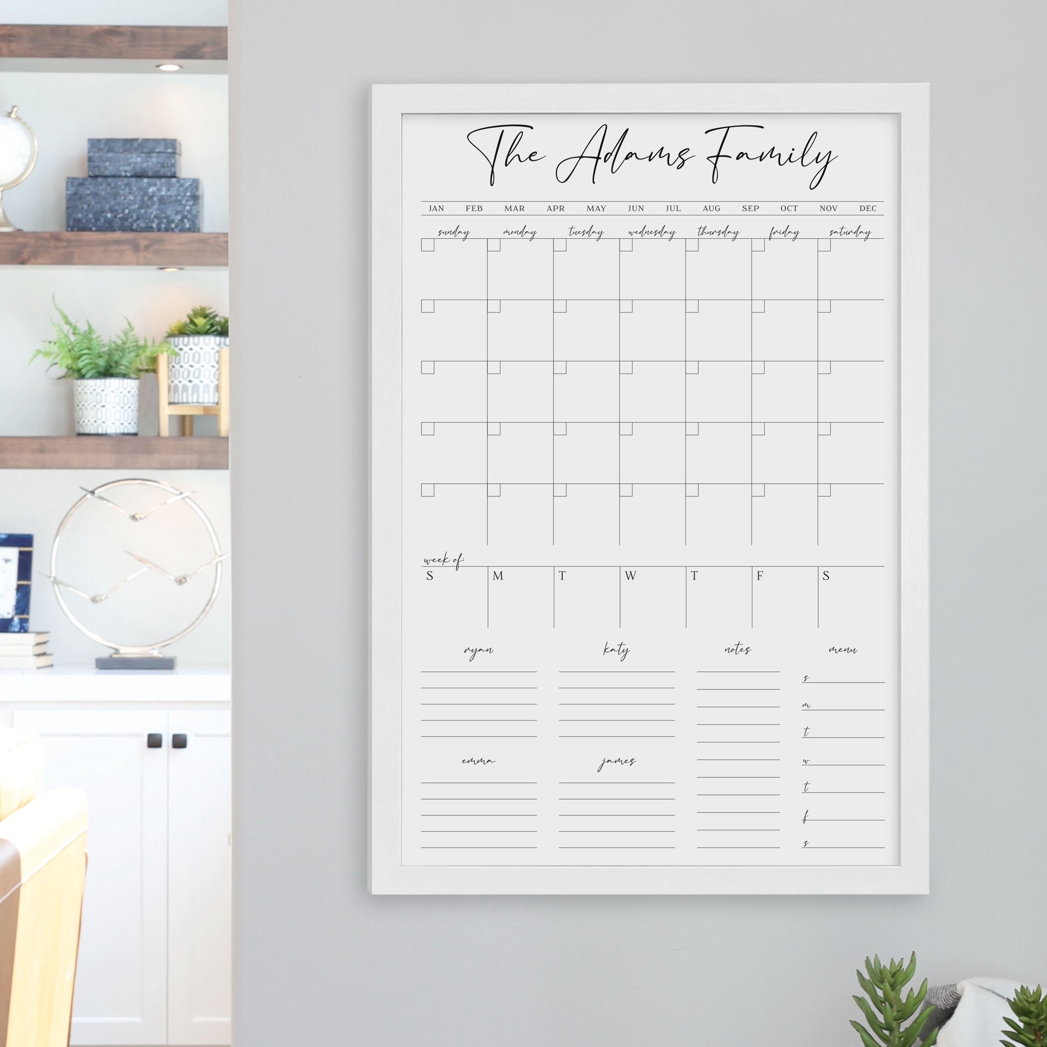 A framed whiteboard calendar with a monthly and weekly format hanging on the wall