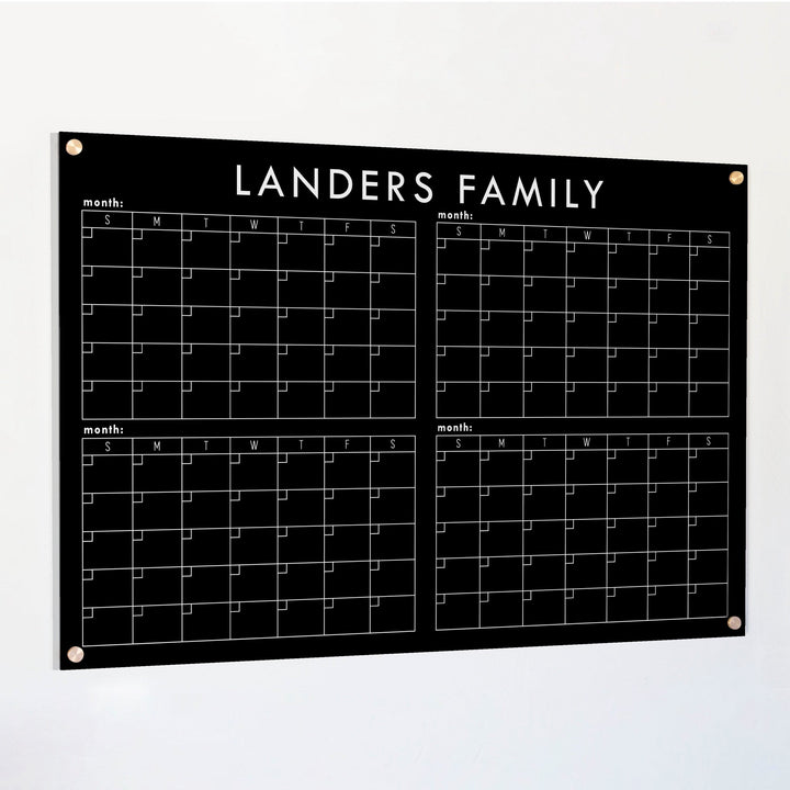 A dry-erase four month calendar made of acrylic hanging on the wall