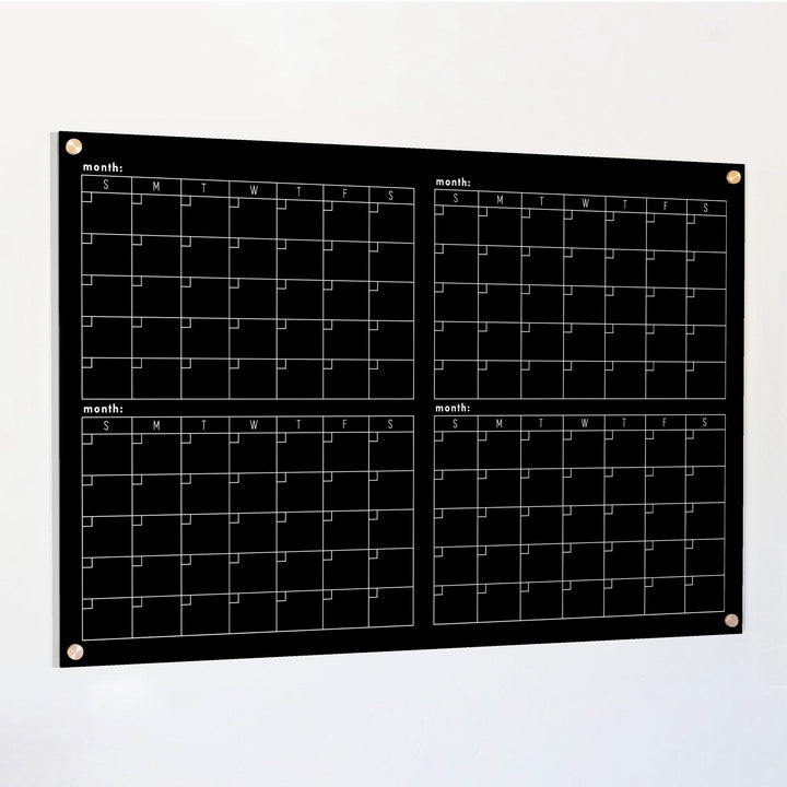 A dry-erase four month calendar made of acrylic hanging on the wall