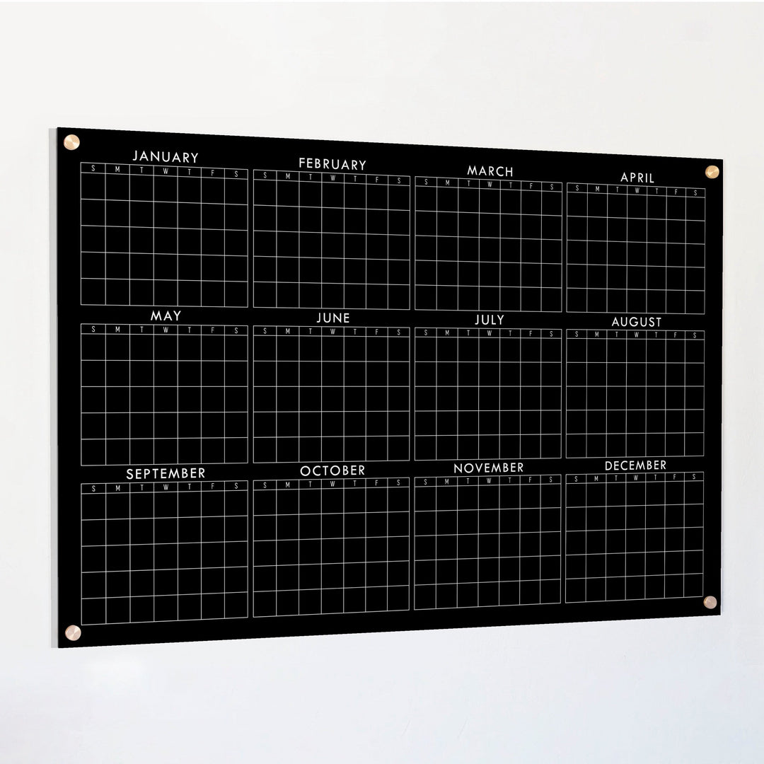 A dry-erase yearly calendar made of acrylic hanging up on the wall
