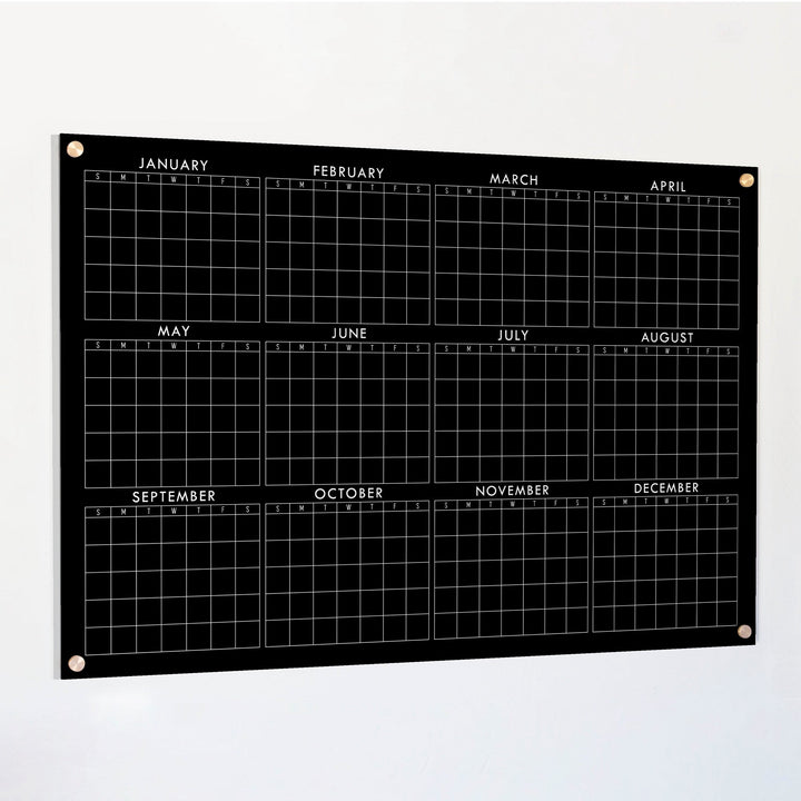 A dry-erase yearly calendar made of acrylic hanging up on the wall