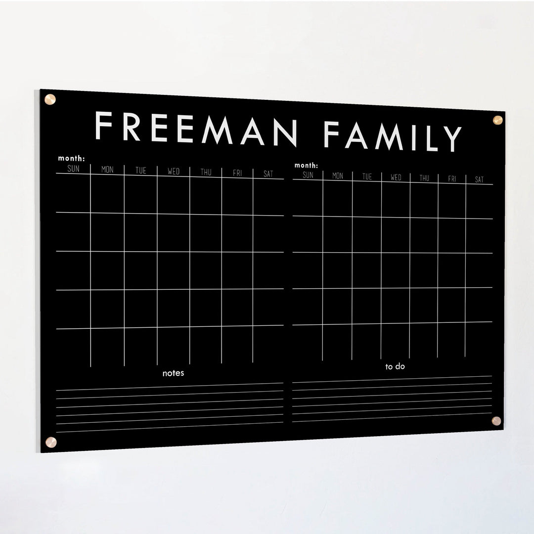 A Dry-erase acrylic calendar with a two month design format hanging on the wall