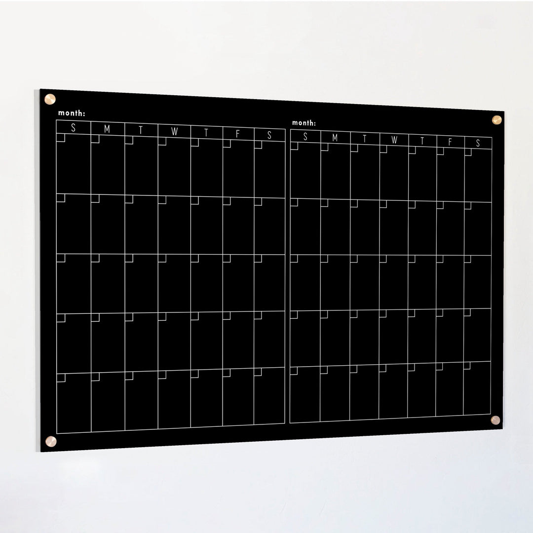 A Dry-erase acrylic calendar with a two month design format hanging on the wall