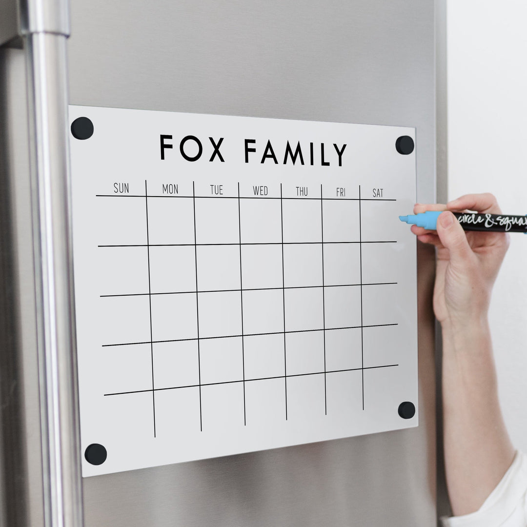 A Dry-erase monthly calender made of magnetic acrylic hanging on the fridge