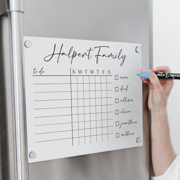 A Dry-erase magnetic acrylic chore chart hanging on the fridge