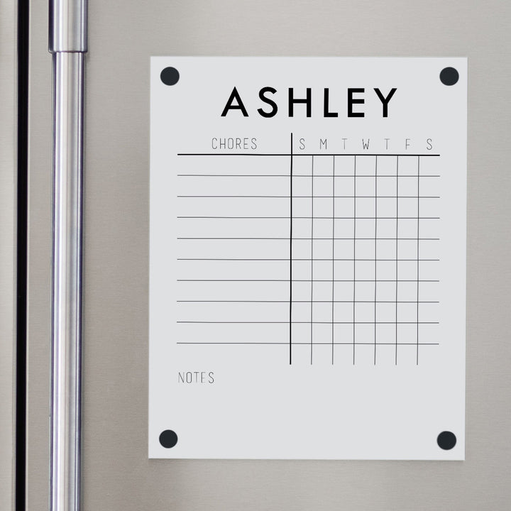 A Dry-erase magnetic acrylic chore chart hanging on the fridge