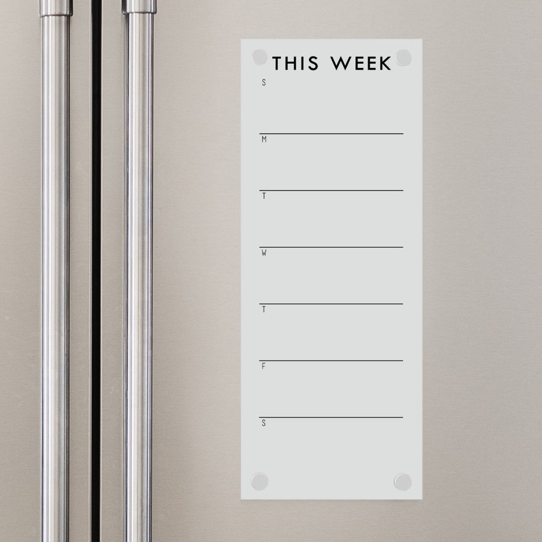 A skinny dry-erase weekly calender made of magnetic acrylic hanging on the fridge