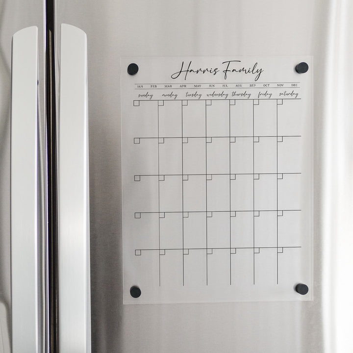 A Dry-erase monthly calender made of magnetic acrylic hanging on the fridge