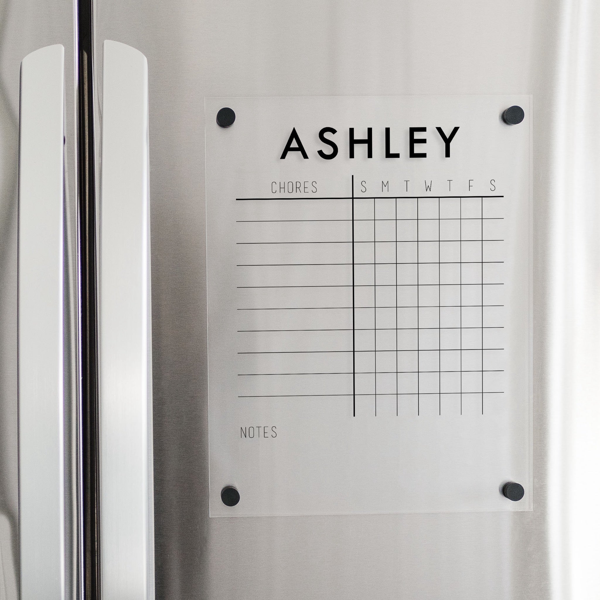 A Dry-erase magnetic acrylic chore chart hanging on the fridge