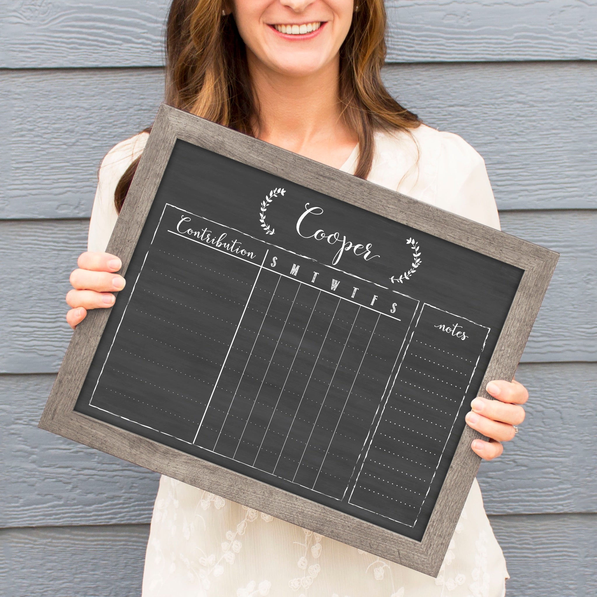 A framed dry-erase chore chart with a chalkboard look hanging on the wall