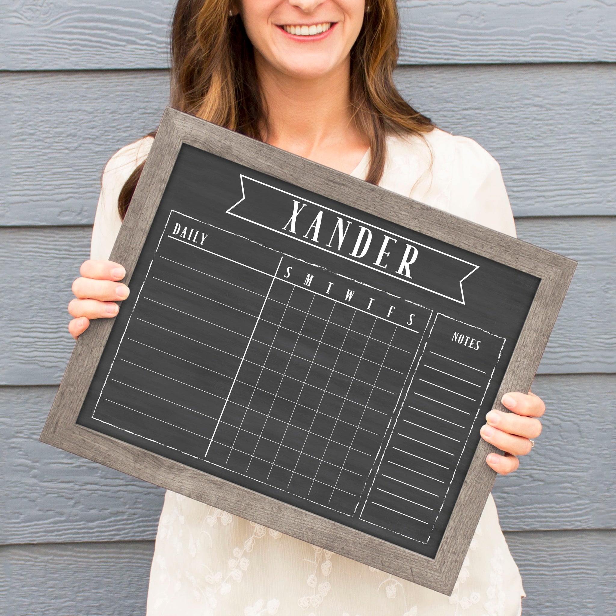 A framed dry-erase chore chart with a chalkboard look hanging on the wall
