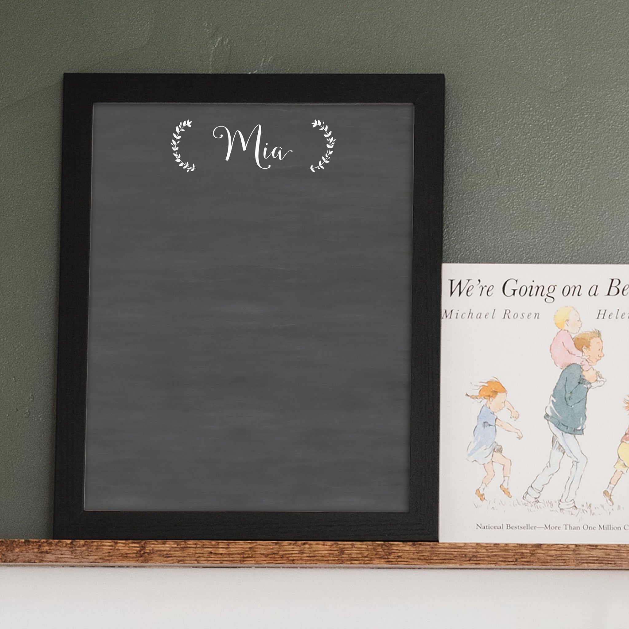 A framed dry-erase chalkboard calendar with a two month design format hanging on the wall