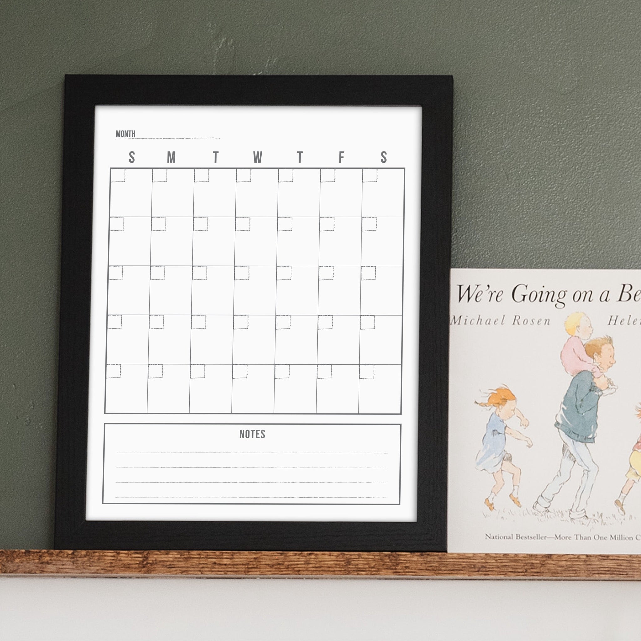 A framed whiteboard monthly calender hanging on the wall