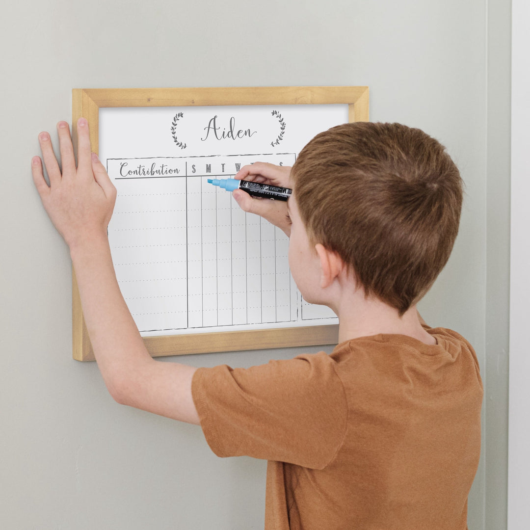 A framed whiteboard chore chart hanging on the wall