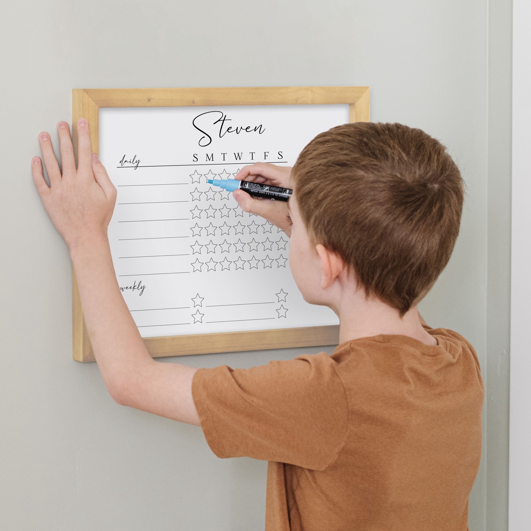 A framed whiteboard reward chart hanging on the wall