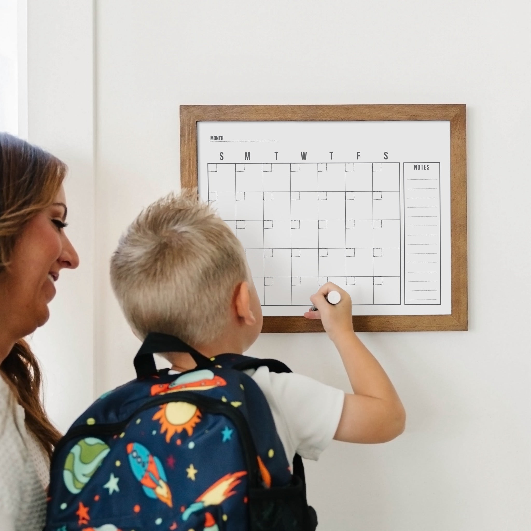 A framed whiteboard monthly calender hanging on the wall