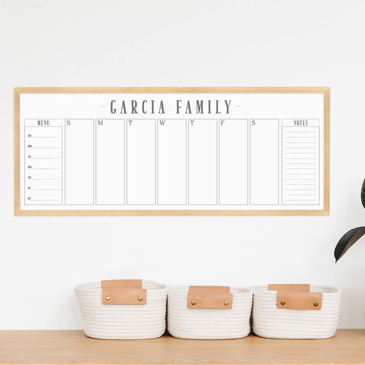 A framed slim whiteboard weekly calender hanging on the wall