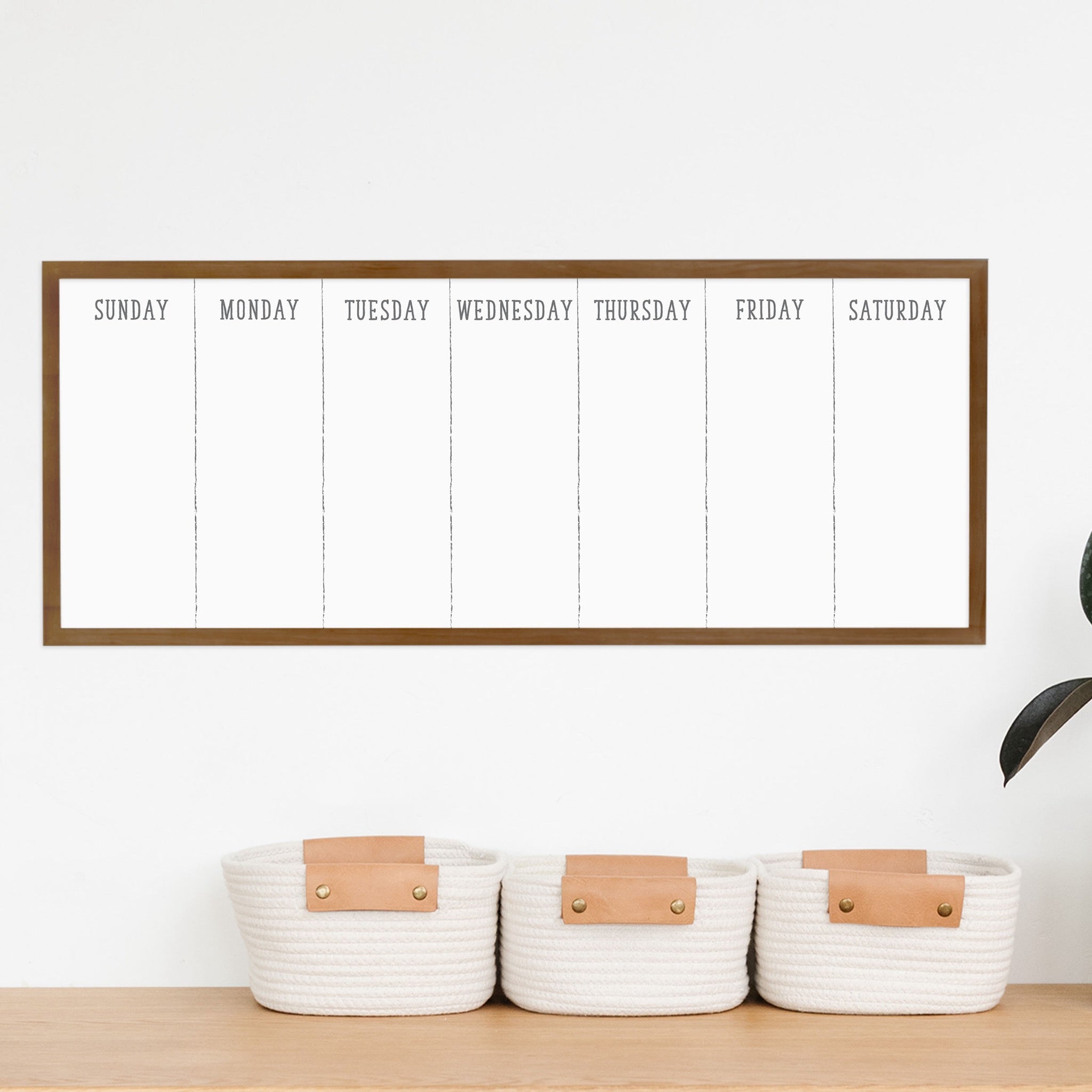 A framed slim whiteboard weekly calender hanging on the wall