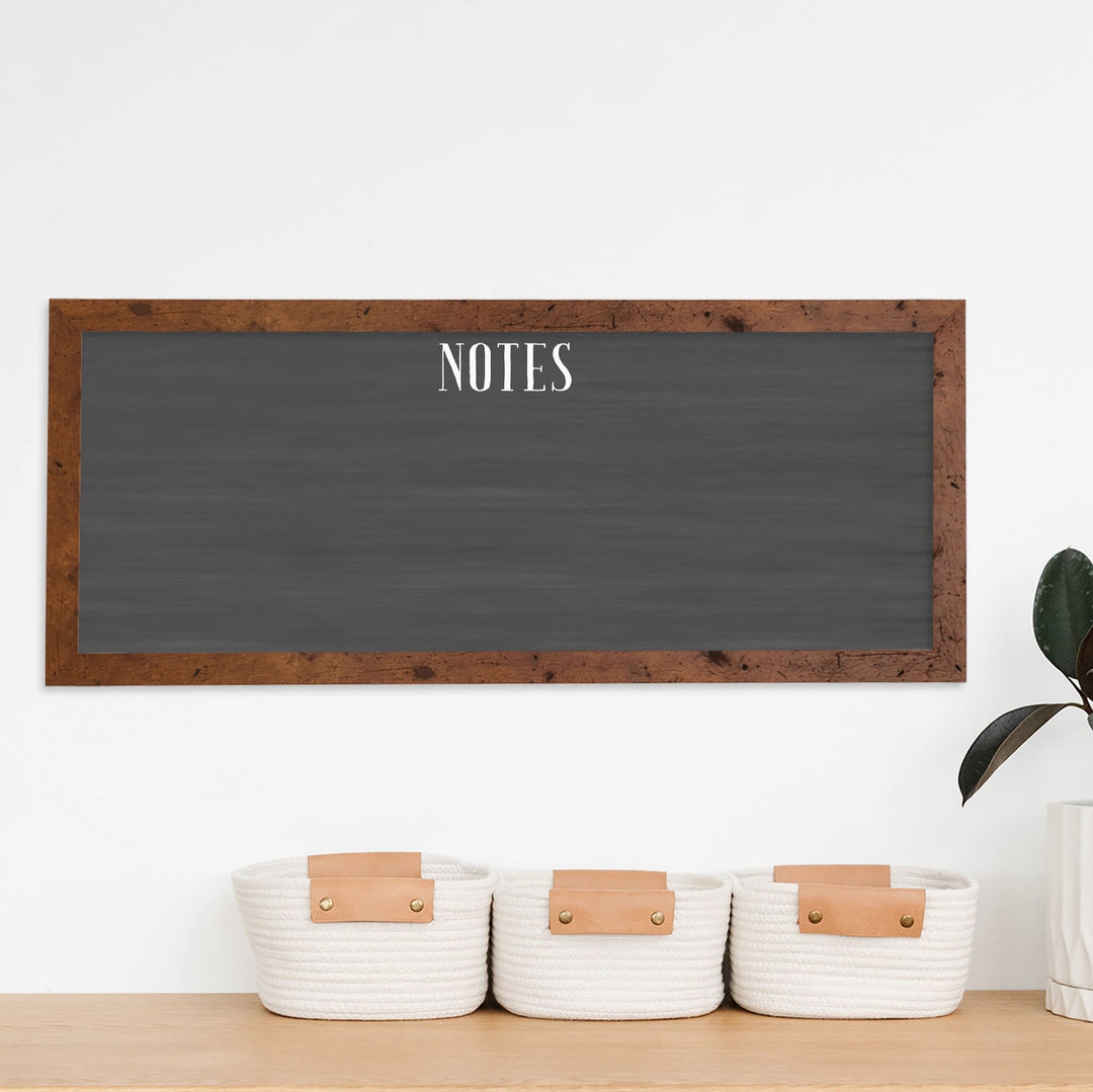 A framed dry-erase chalkboard calendar with a two month design format hanging on the wall
