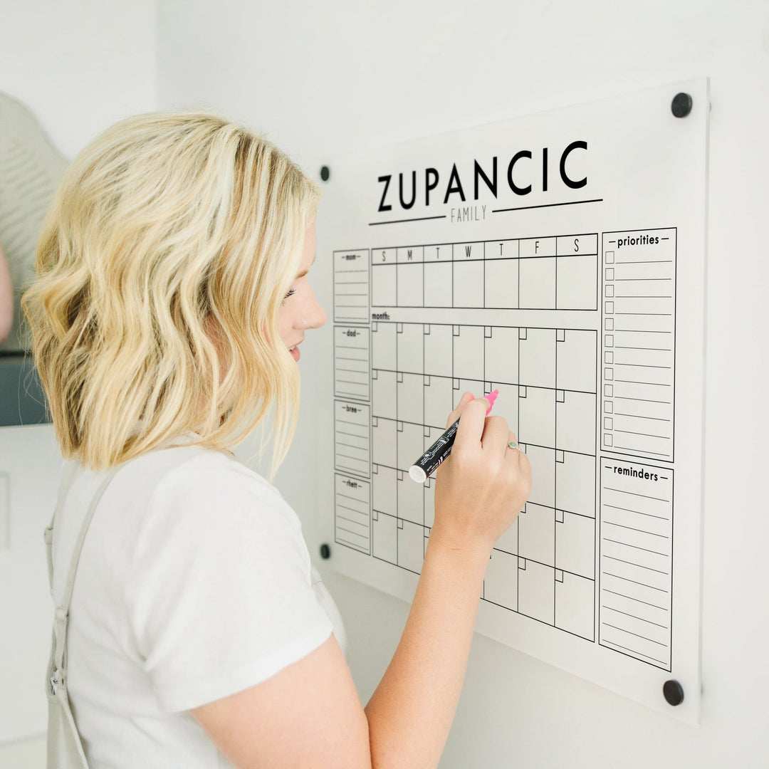 A Dry-erase calendar with a monthly and weekly format made of acrylic hanging on the wall