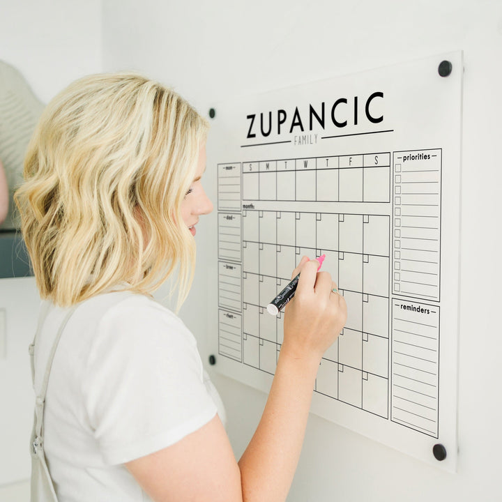A Dry-erase calendar with a monthly and weekly format made of acrylic hanging on the wall