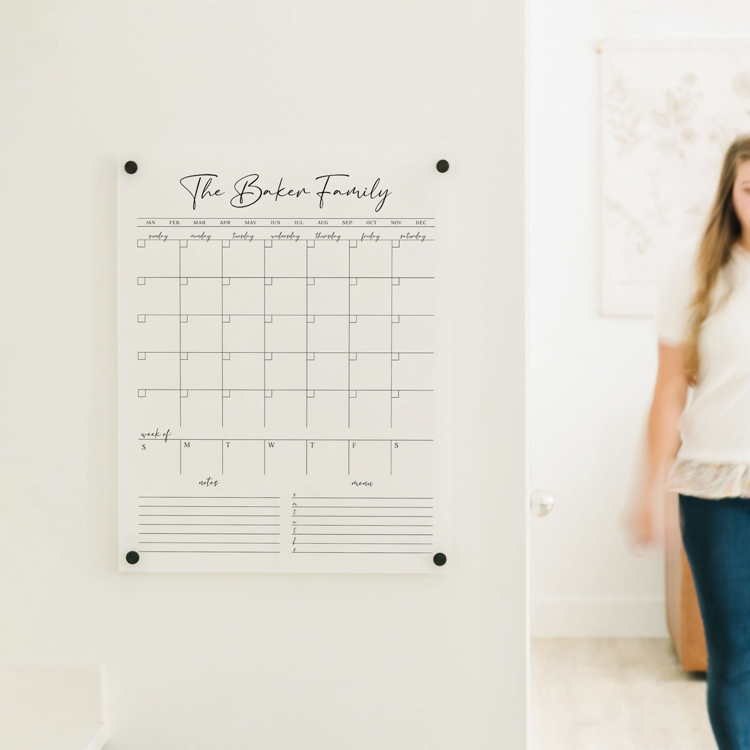 A Dry-erase calendar with a monthly and weekly format made of acrylic hanging on the wall