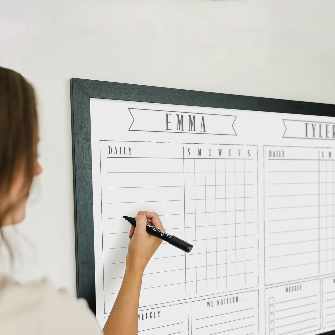 A framed whiteboard chore chart hanging on the wall