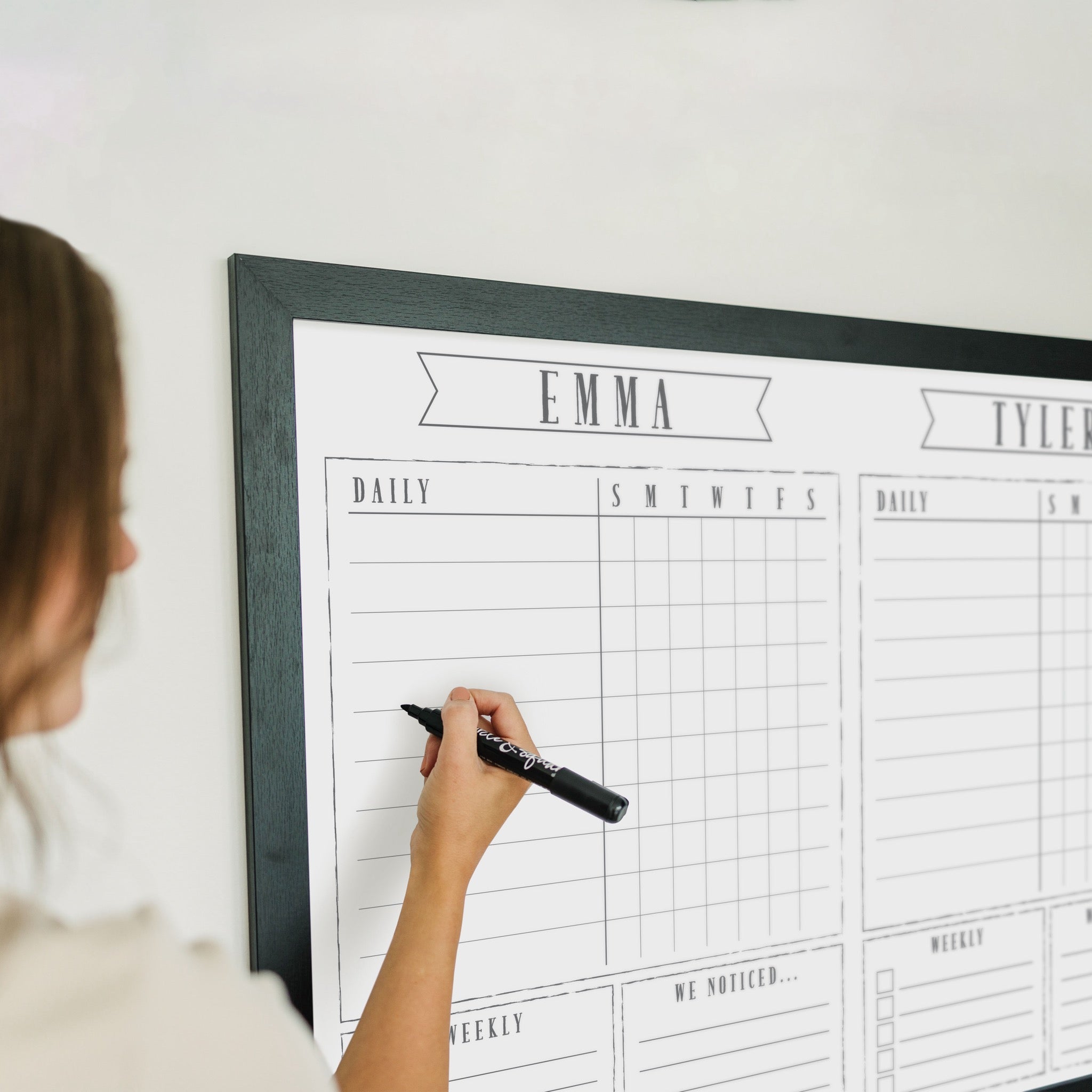 A framed whiteboard chore chart hanging on the wall