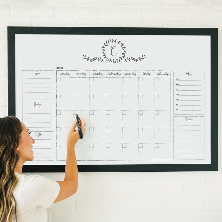 A framed whiteboard family command center hanging on the wall