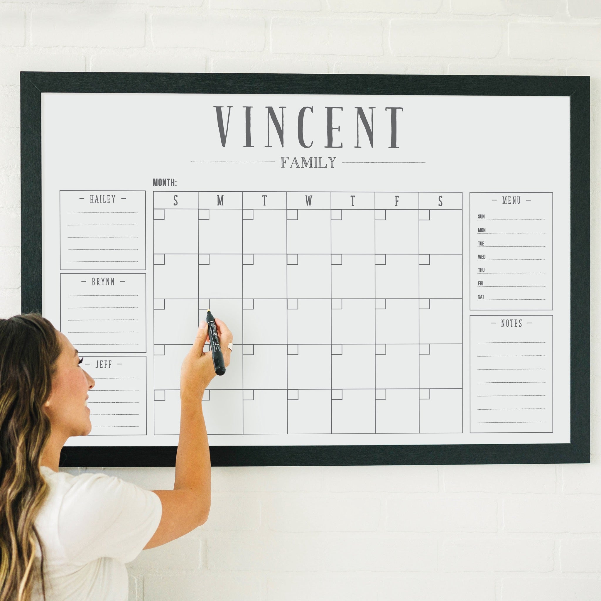 A framed whiteboard family command center hanging on the wall