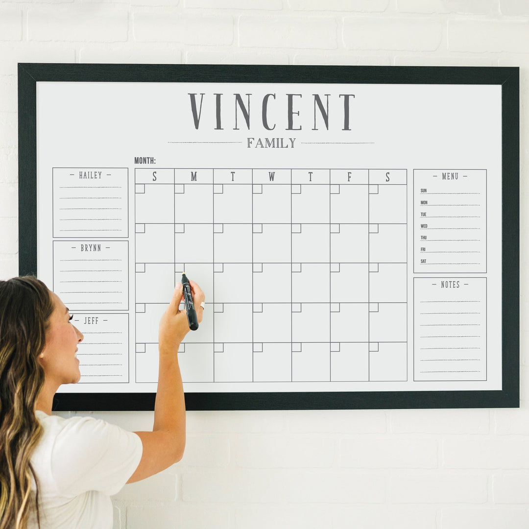 A framed whiteboard family command center hanging on the wall