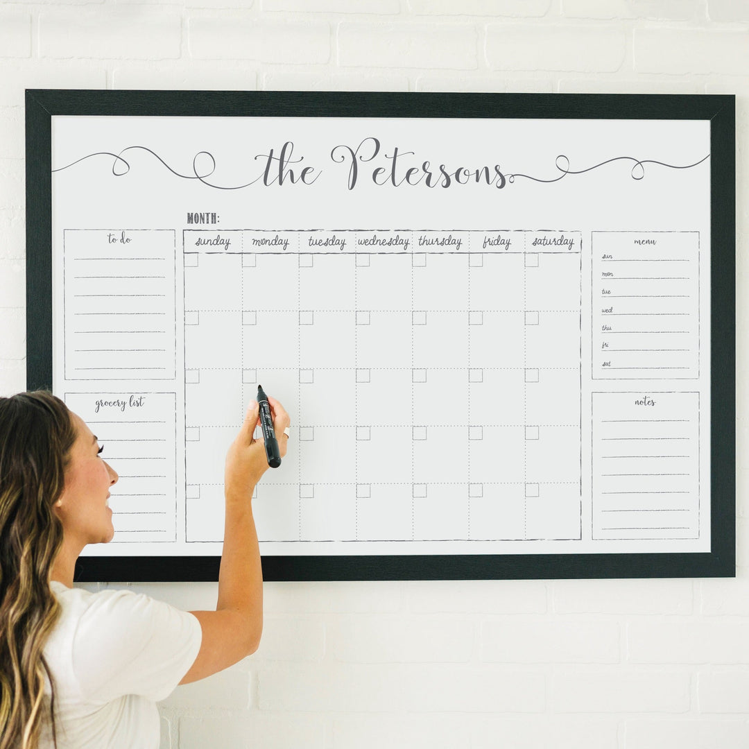 A framed whiteboard family command center hanging on the wall