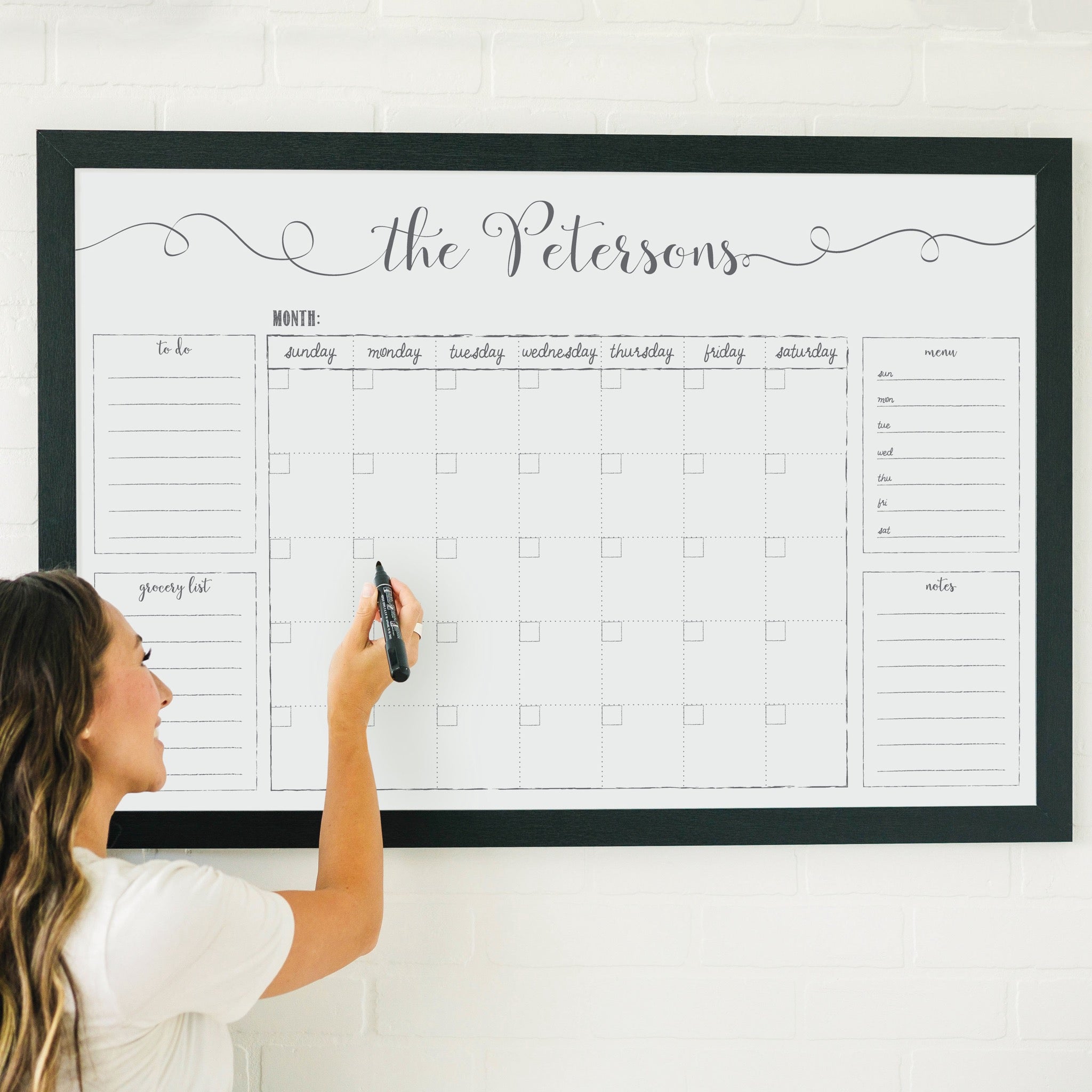 A framed whiteboard family command center hanging on the wall