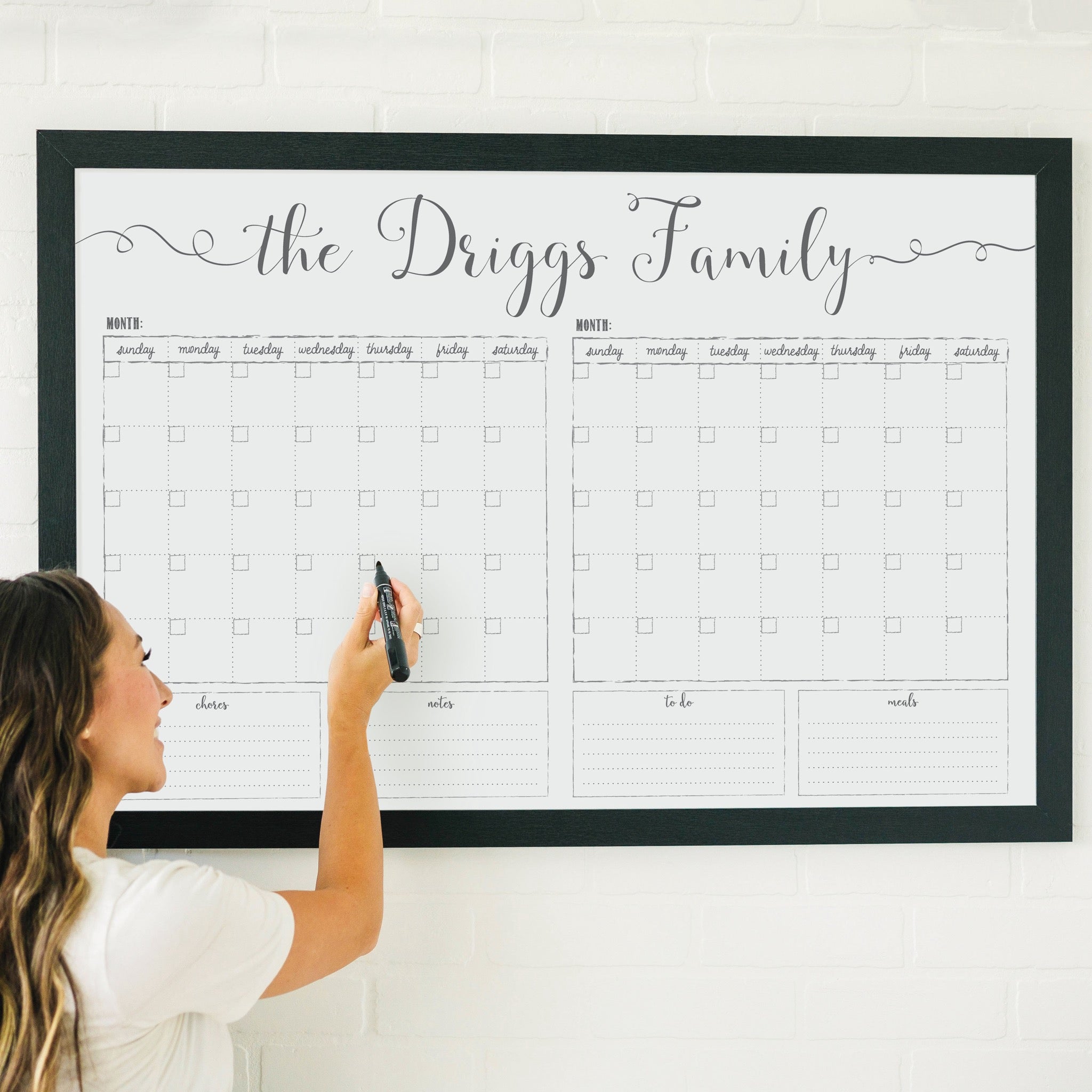 A framed whiteboard calendar with a two month design format hanging on the wall