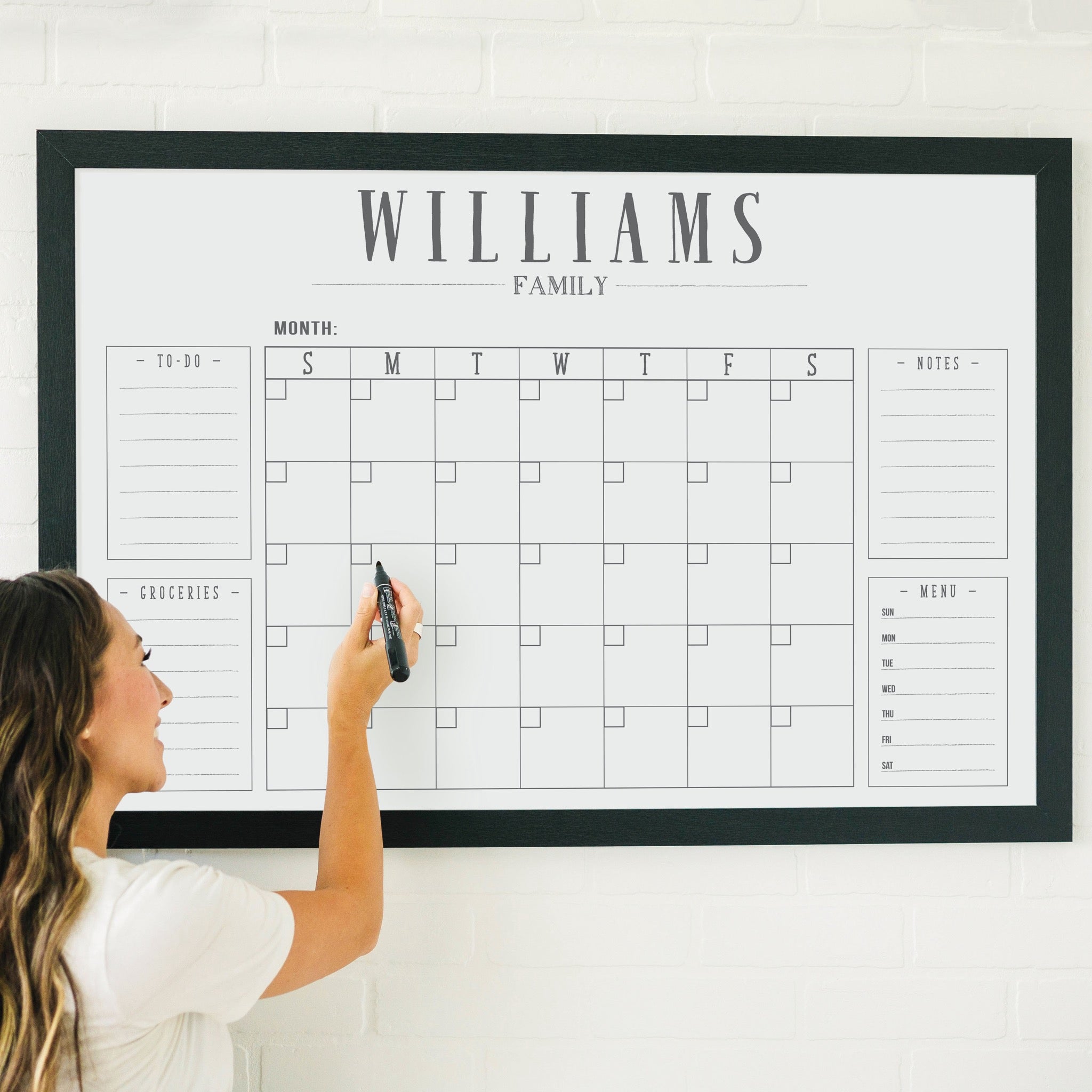 A framed whiteboard family command center hanging on the wall