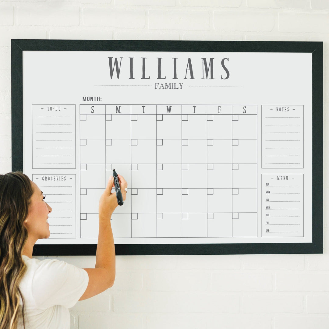 A framed whiteboard family command center hanging on the wall
