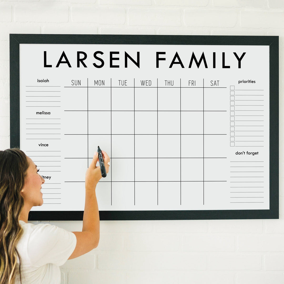 A framed whiteboard family command center hanging on the wall