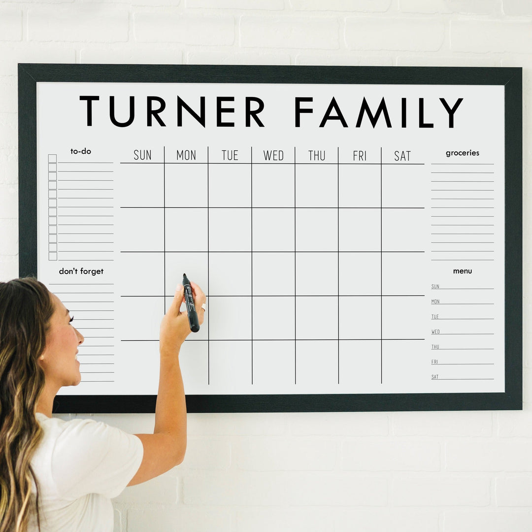 A framed whiteboard family command center hanging on the wall