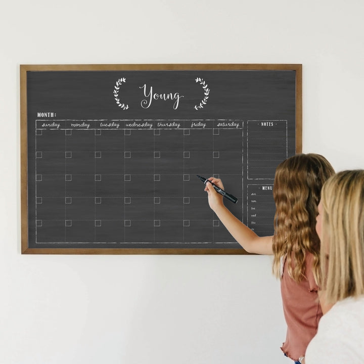 A framed whiteboard monthly calender hanging on the wall